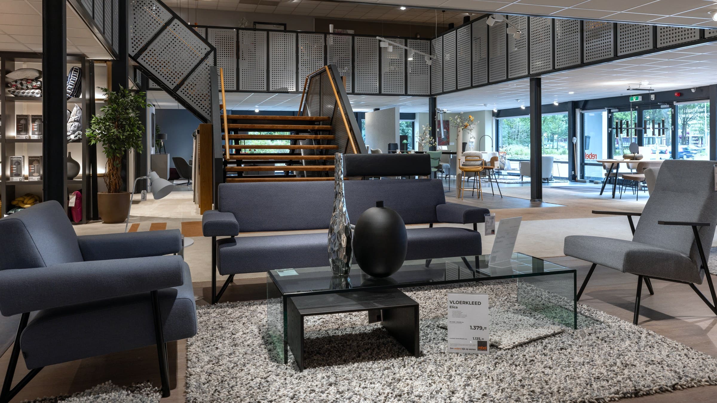 Frisse showroom bij Rebel Wonen & Slapen in Huizen met fauteuils, vloerkleed, trap en daglicht